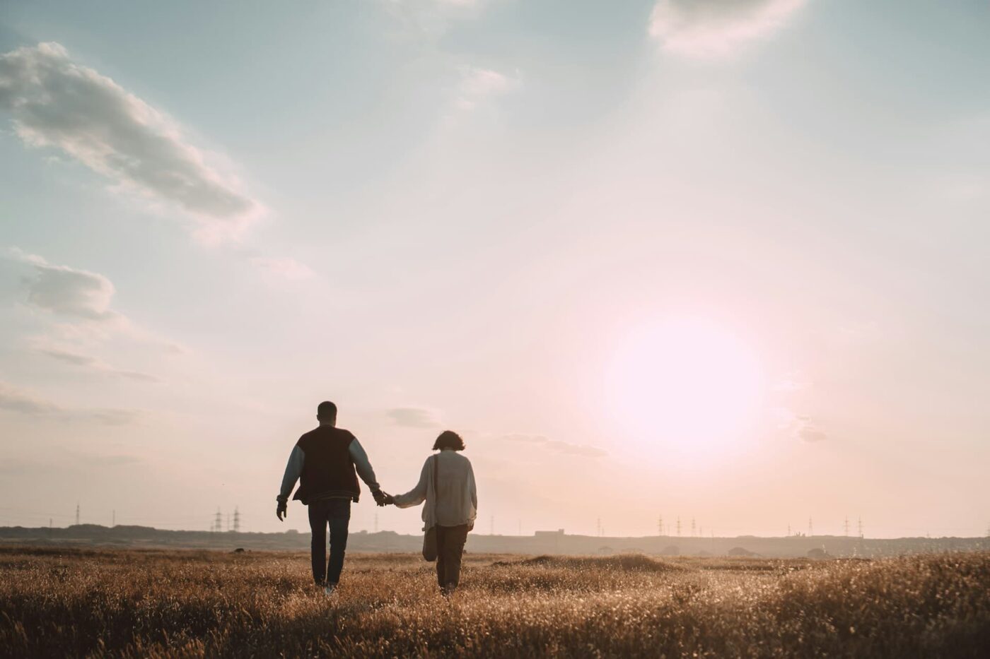 couple-holding-hands-while-walking-on-grass-field-during-daytime