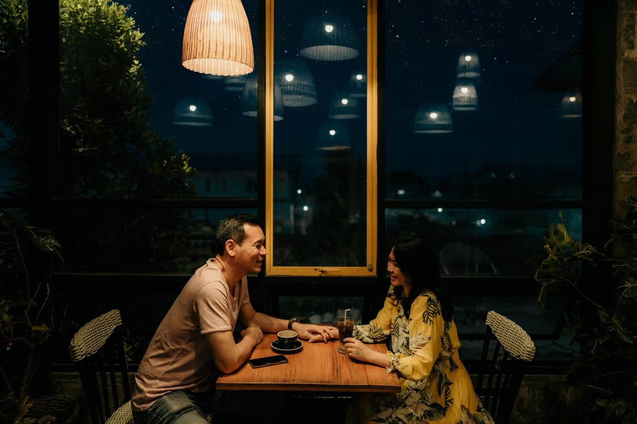 man-and-woman-sitting-on-brown-wooden-table